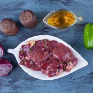 Fresh raw chicken hearts on a gray plate with pink Himalayan salt, red peppercorns, and cherry tomato halves — Choice A Chicken Center.